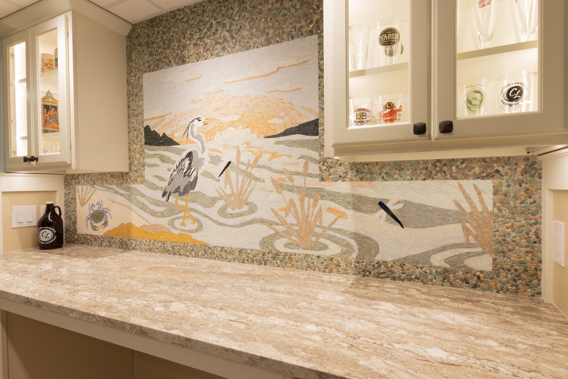 A kitchen counter with a painting on the wall above it.