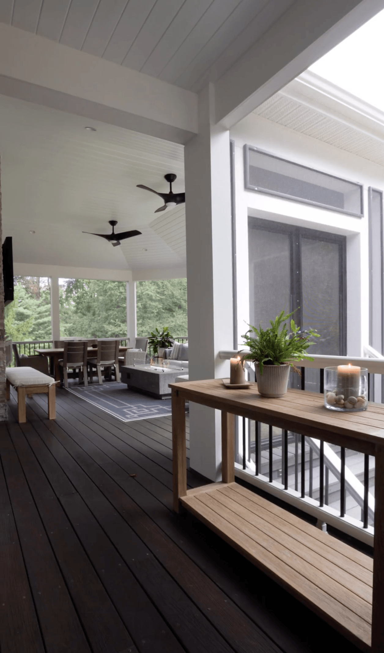 A porch with a wooden table and a ceiling fan.