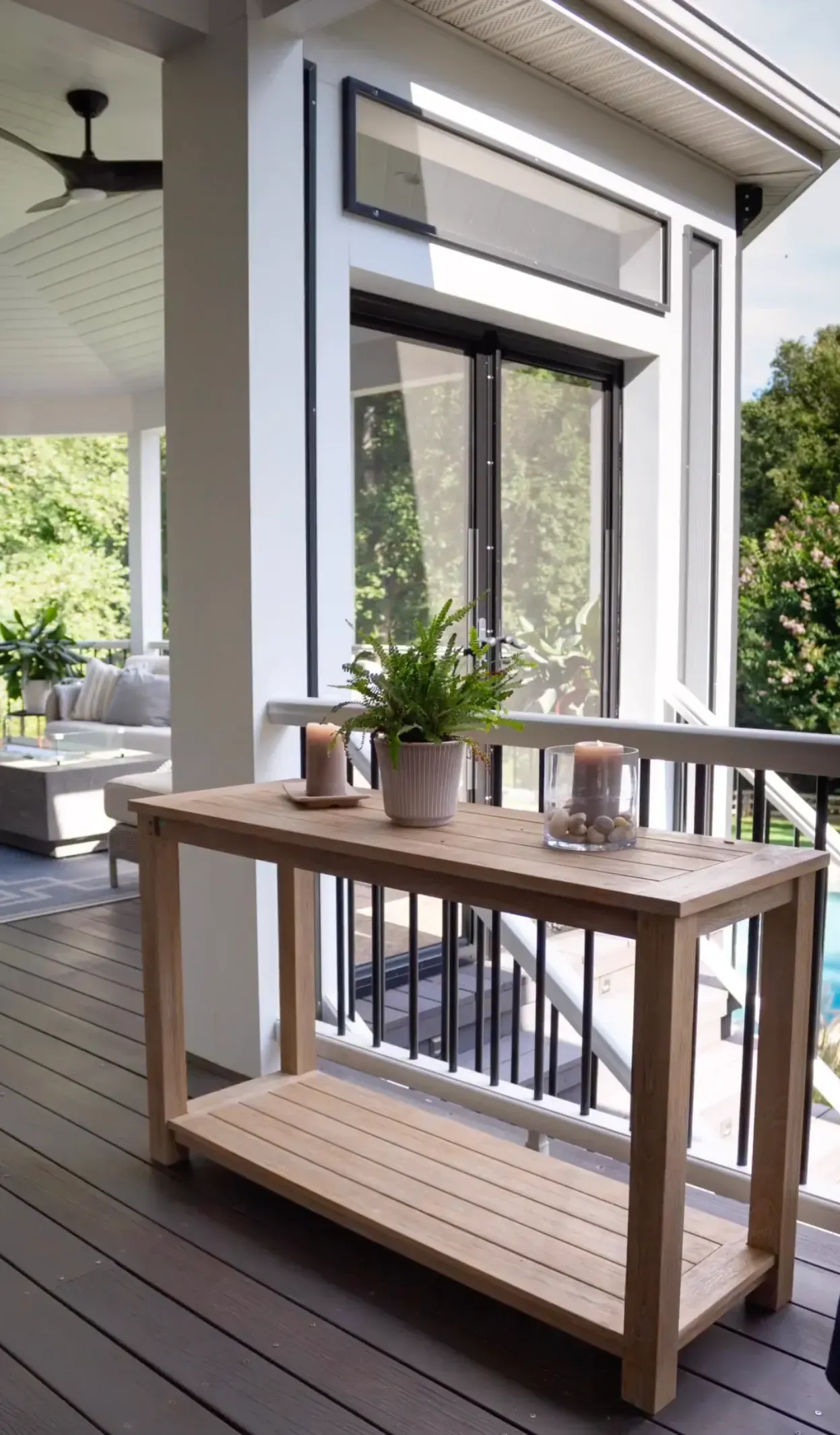 A wooden table is sitting on a porch next to a window.