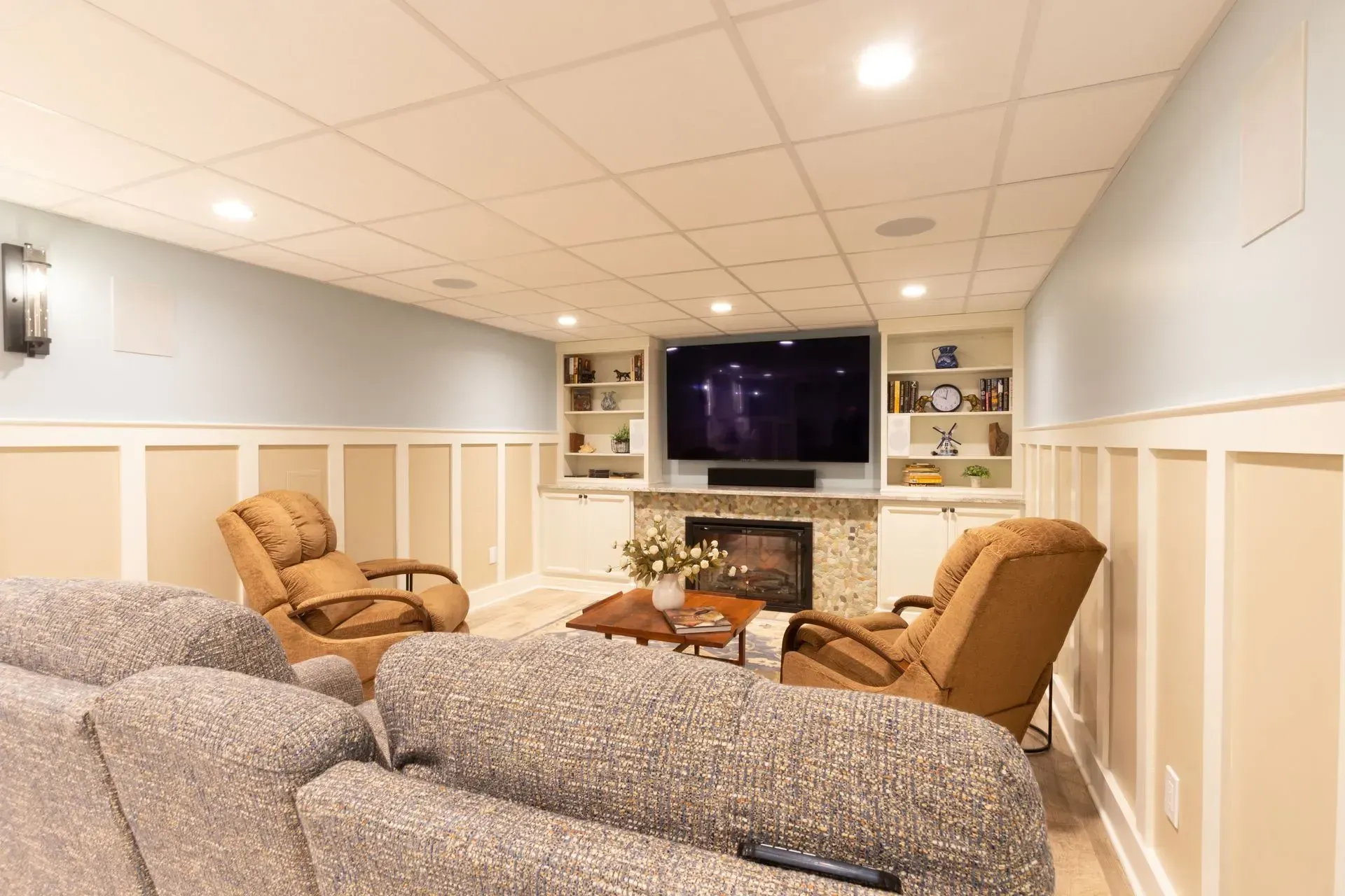 A living room with a couch , chairs , a fireplace and a flat screen tv.