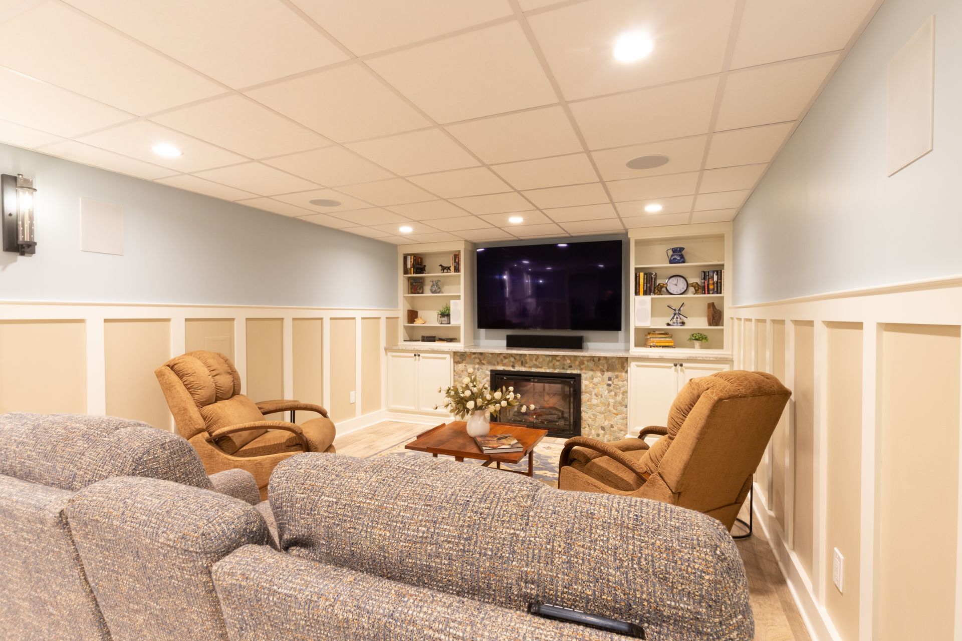 A living room with a couch , chairs , a fireplace and a flat screen tv.