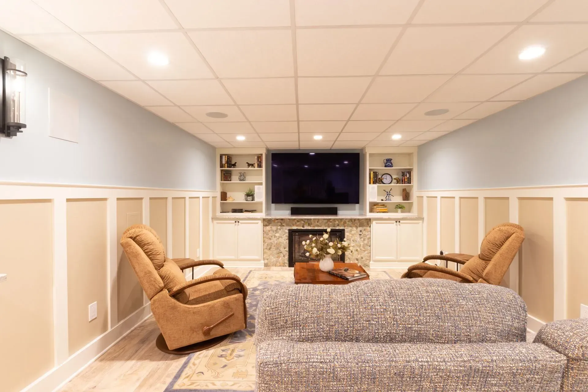 A living room with a couch , chairs , and a flat screen tv.