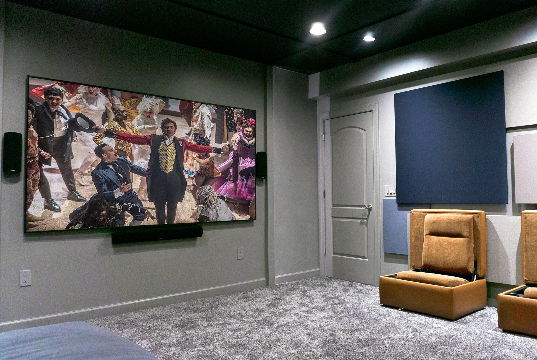 A home theater with two chairs and a large screen on the wall.