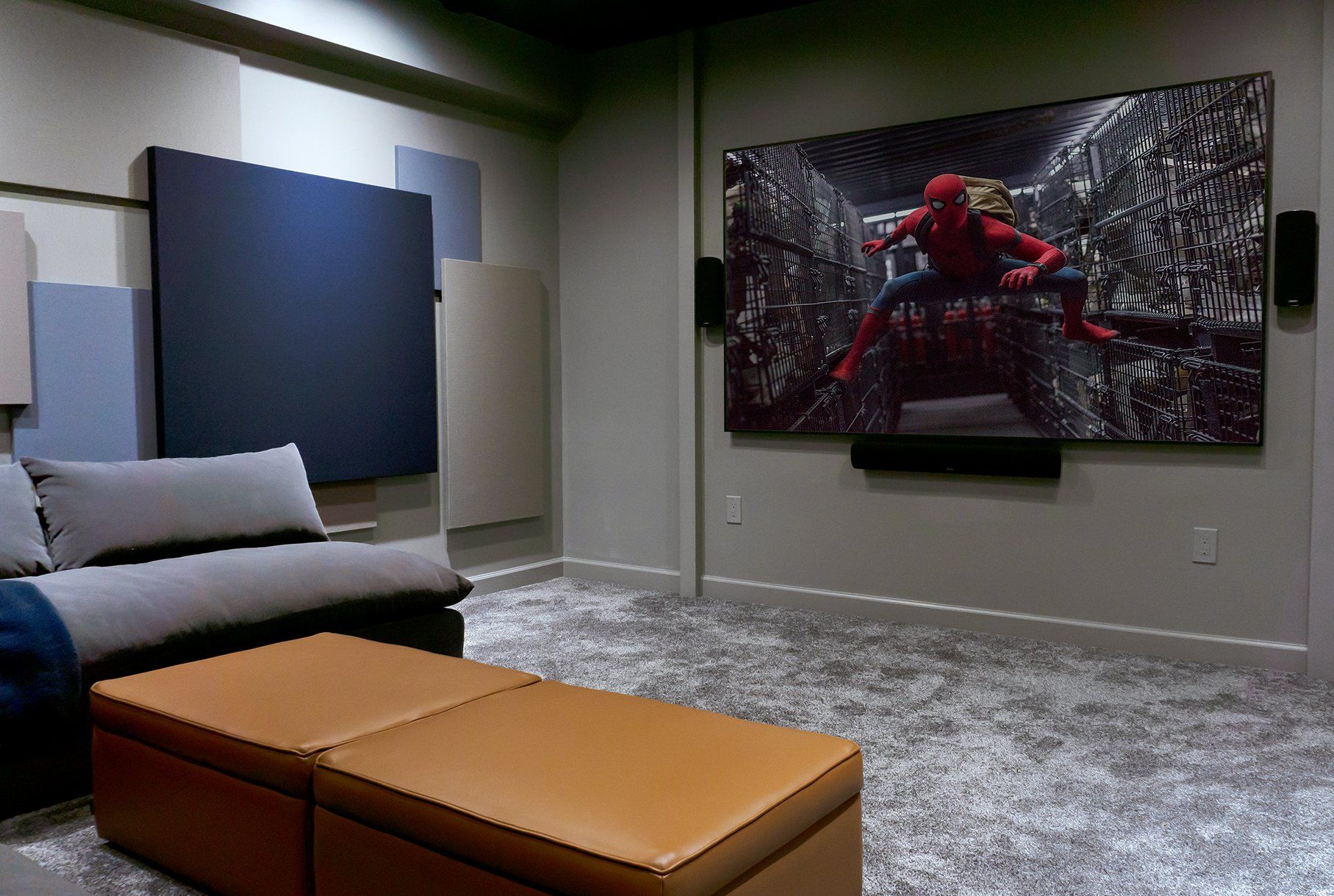 A home theater with a couch , ottoman , and a large screen.