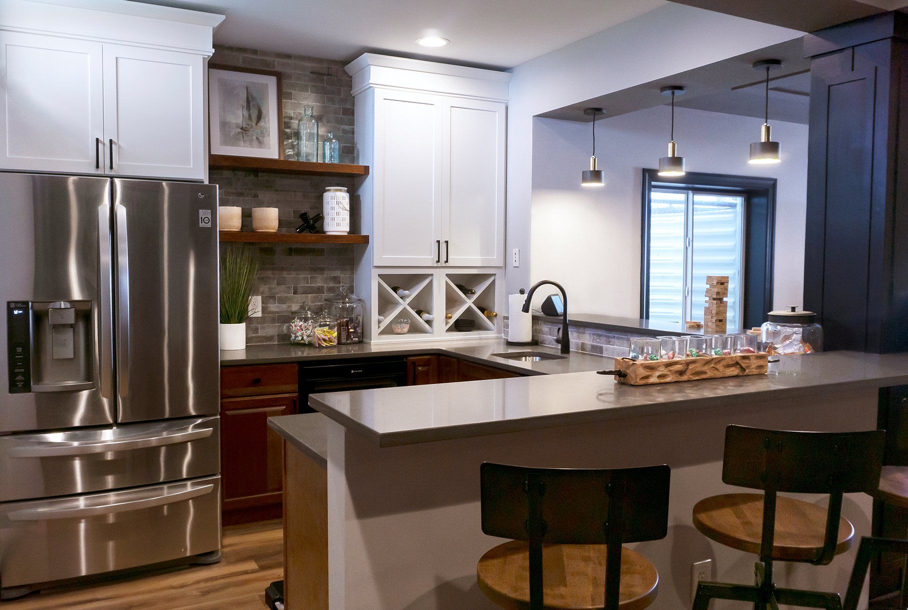 A kitchen with stainless steel appliances , a refrigerator , a sink , and a bar.