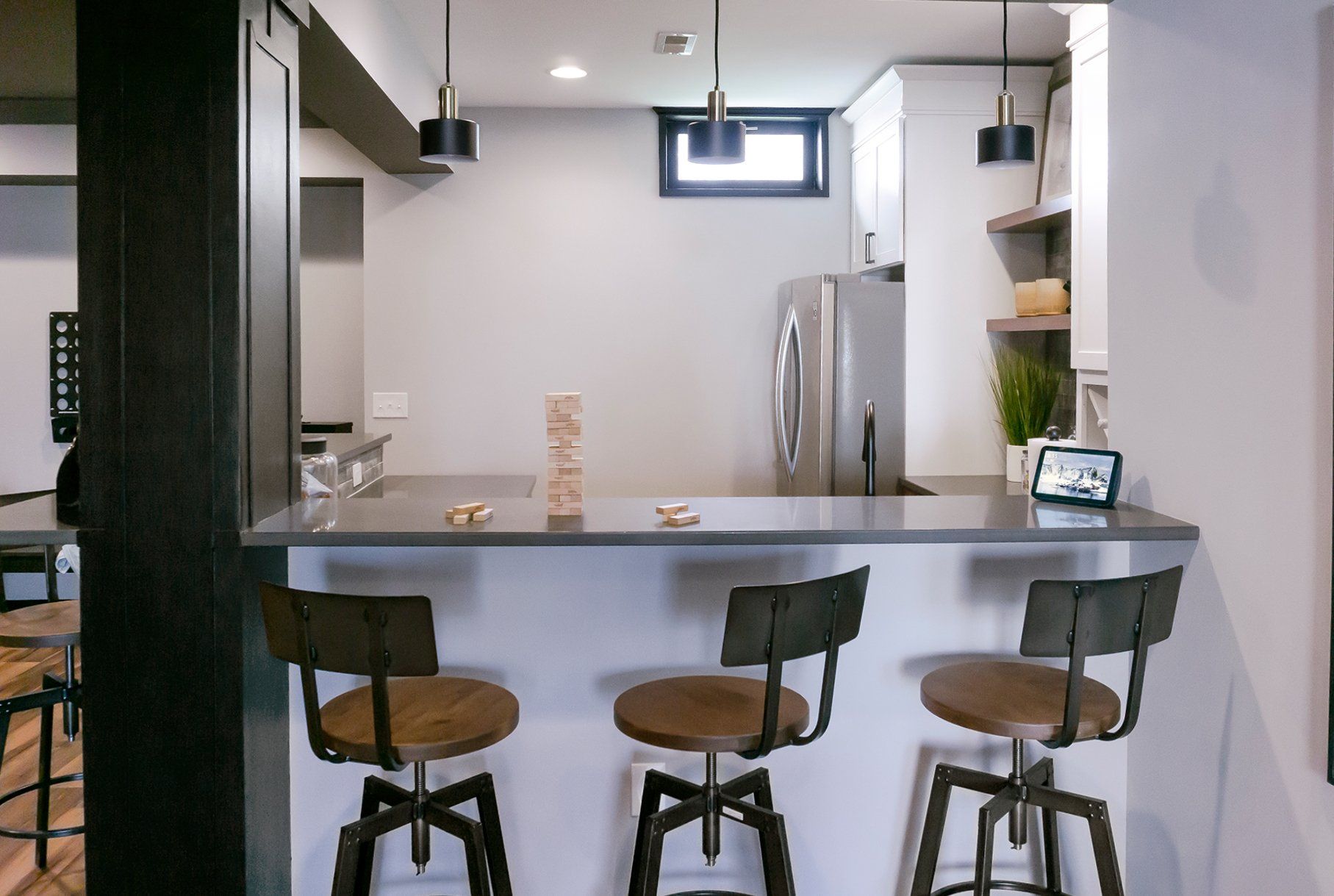 A kitchen with a stainless steel refrigerator and three bar stools