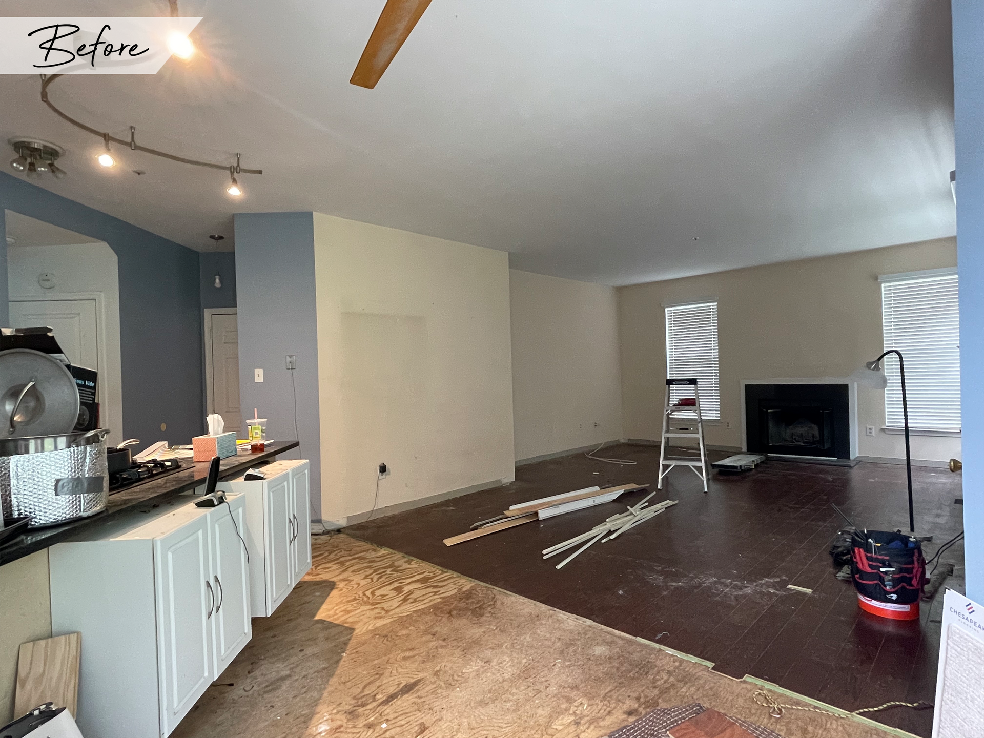 A living room with a fireplace and a ceiling fan before being remodeled.