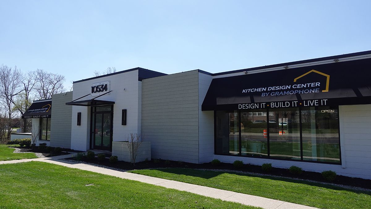A white building with a black awning on the side of it.