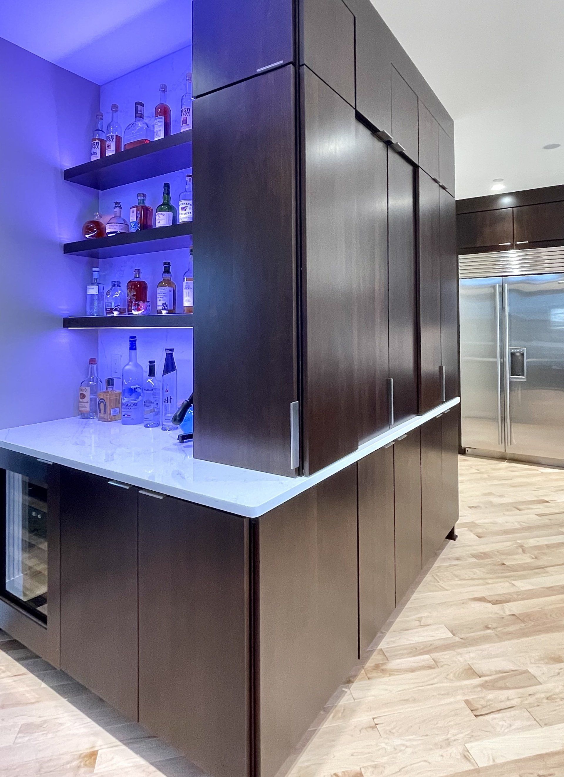 A kitchen with a bar and bottles on shelves