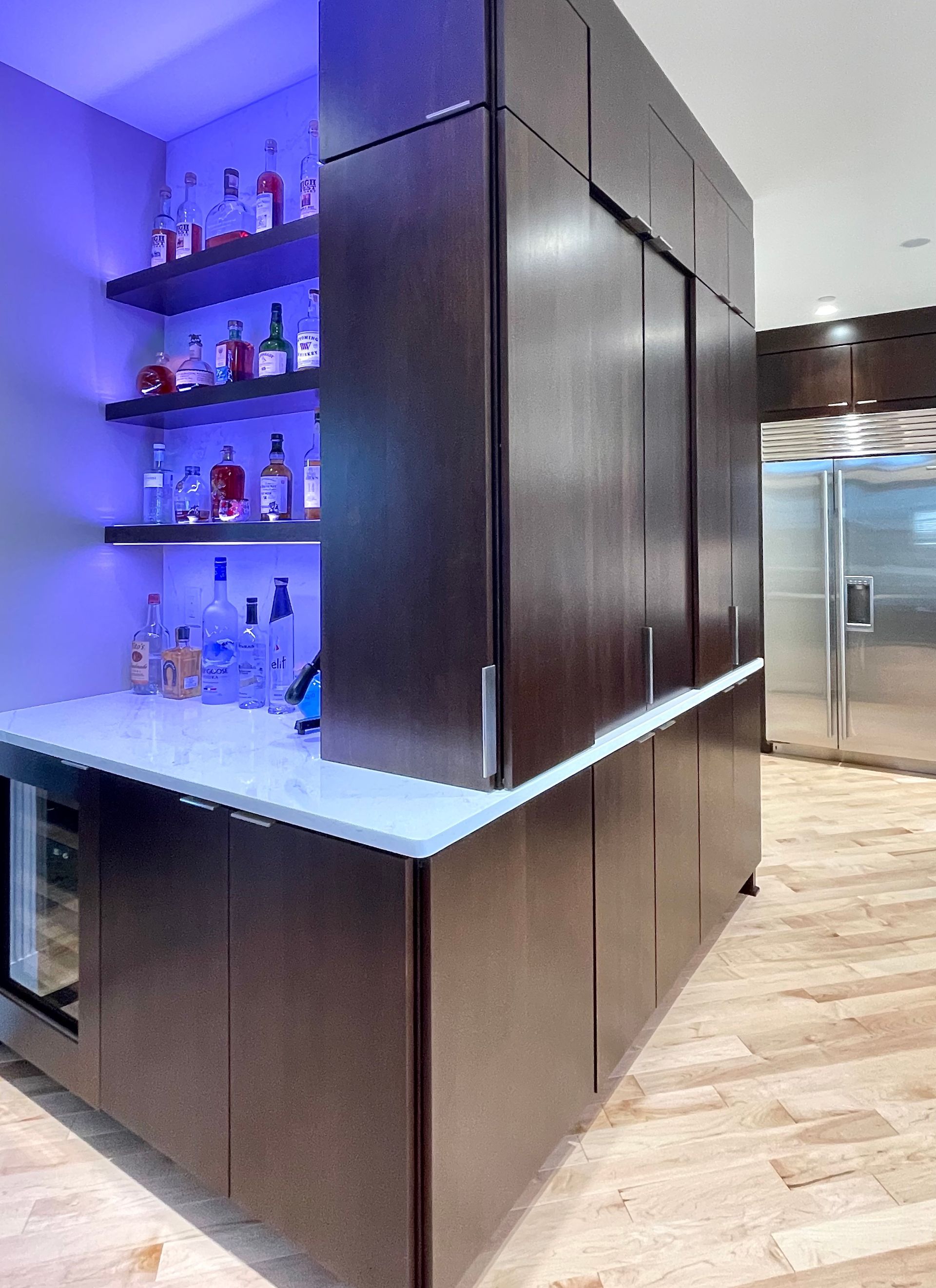 A kitchen with a bar and bottles on shelves