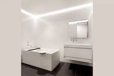 A bathroom with a bathtub , sink and mirror.
