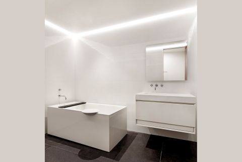 A bathroom with a bathtub , sink and mirror.
