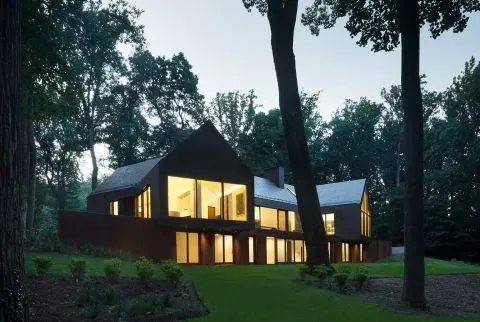 A large house with a lot of windows is surrounded by trees