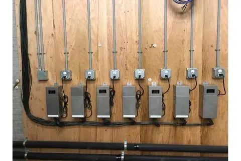 A row of electrical boxes hanging on a wooden wall.