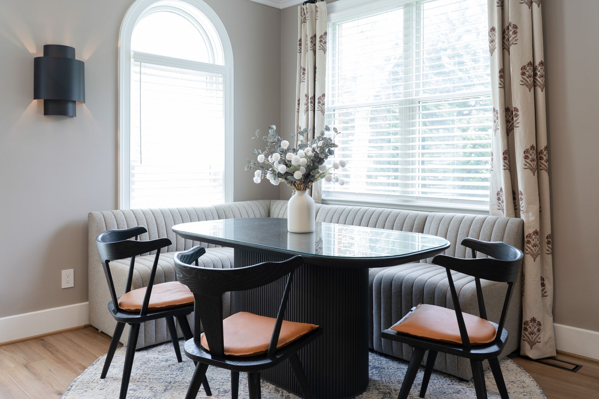 A dining room with a table and chairs in front of a window.