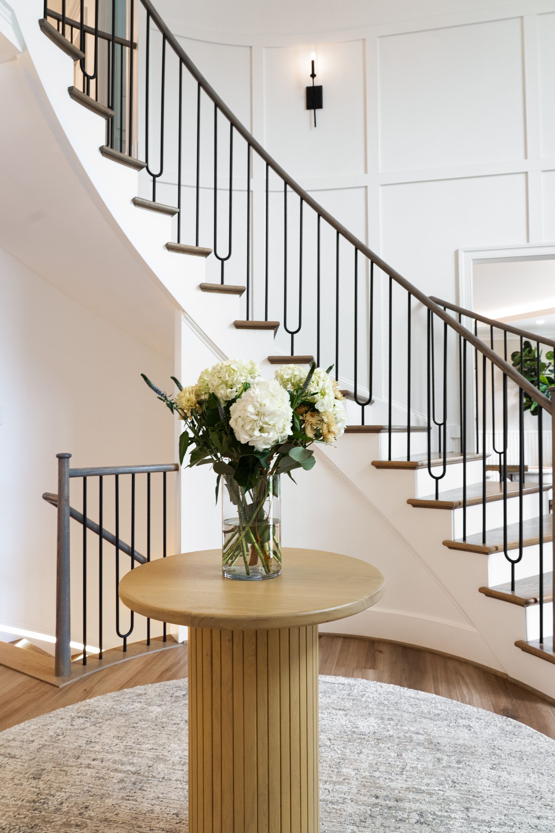 A table with flowers on it in front of a spiral staircase.