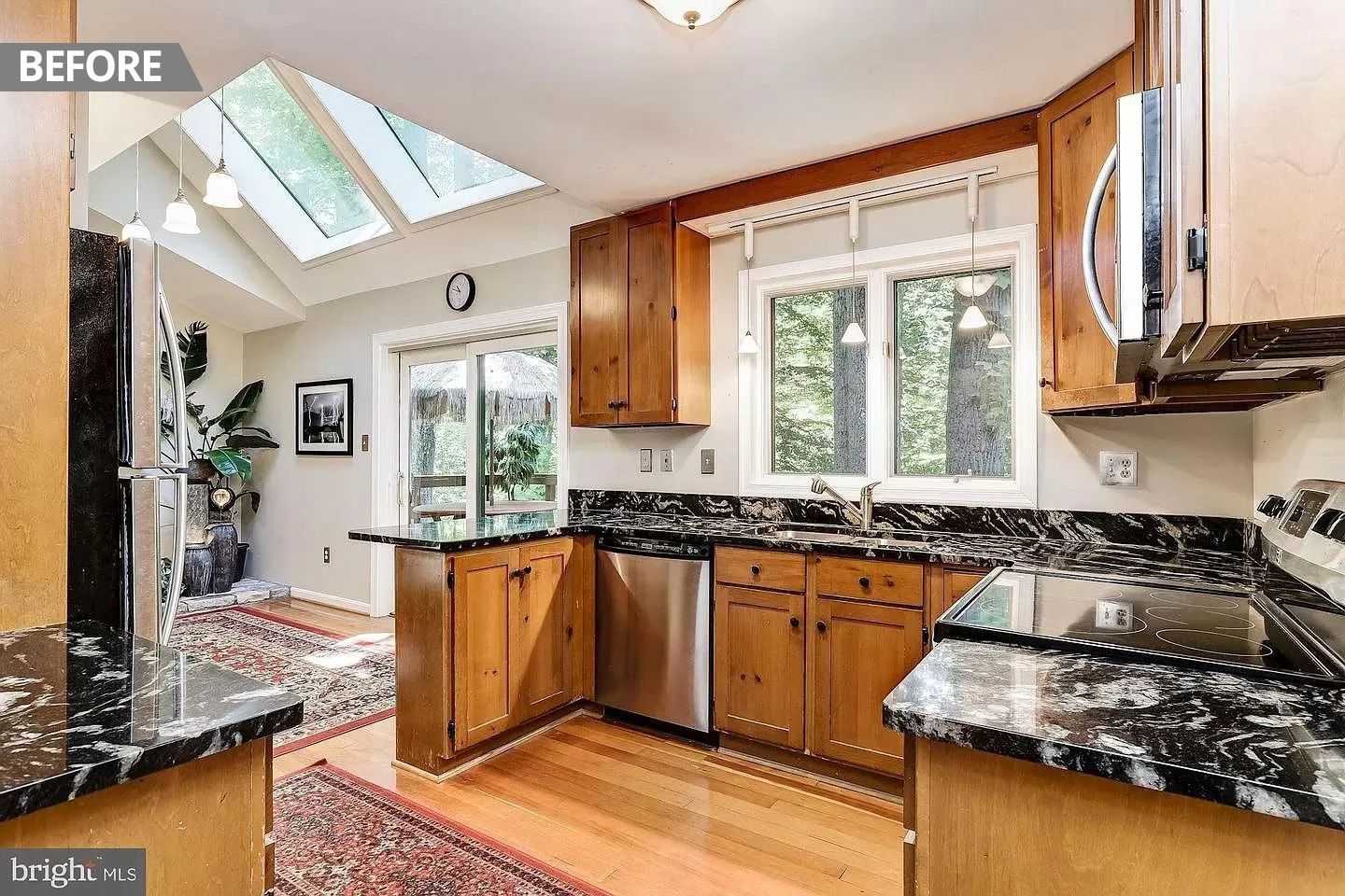 A kitchen with wooden cabinets , granite counter tops , stainless steel appliances and a skylight.