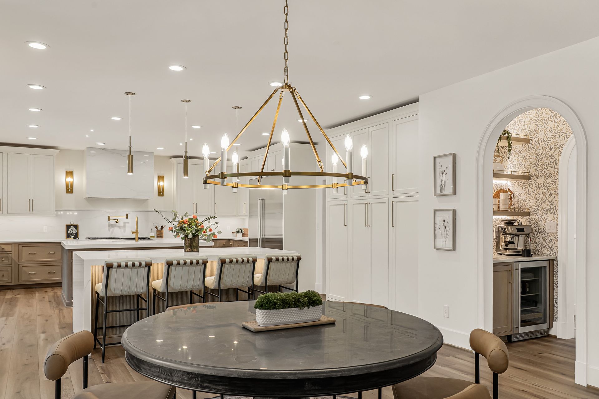 A dining room with a round table and chairs and a chandelier hanging from the ceiling.