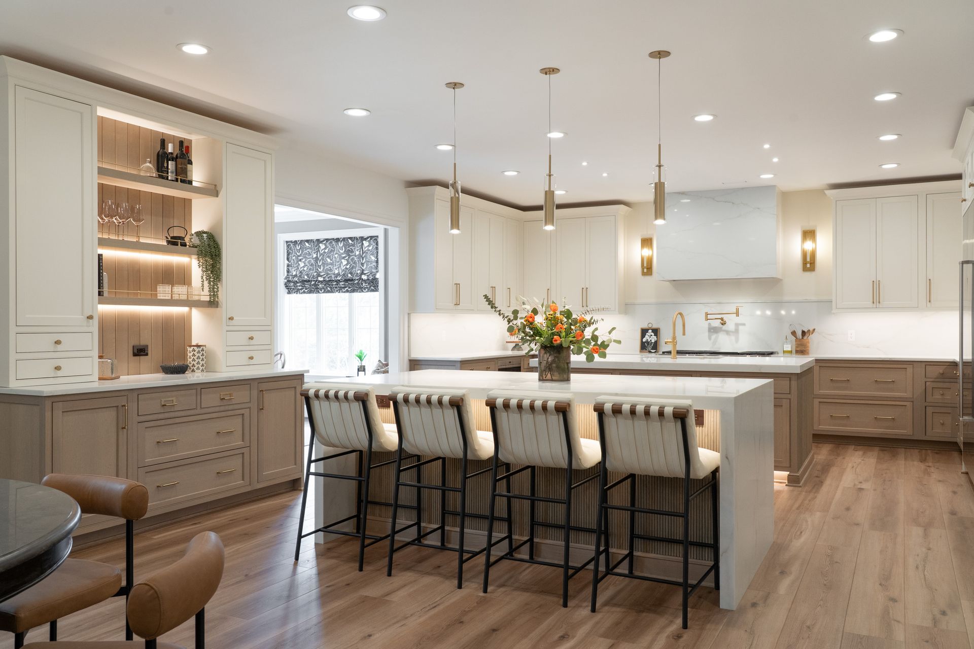 A kitchen with white cabinets and wooden floors and a large island.