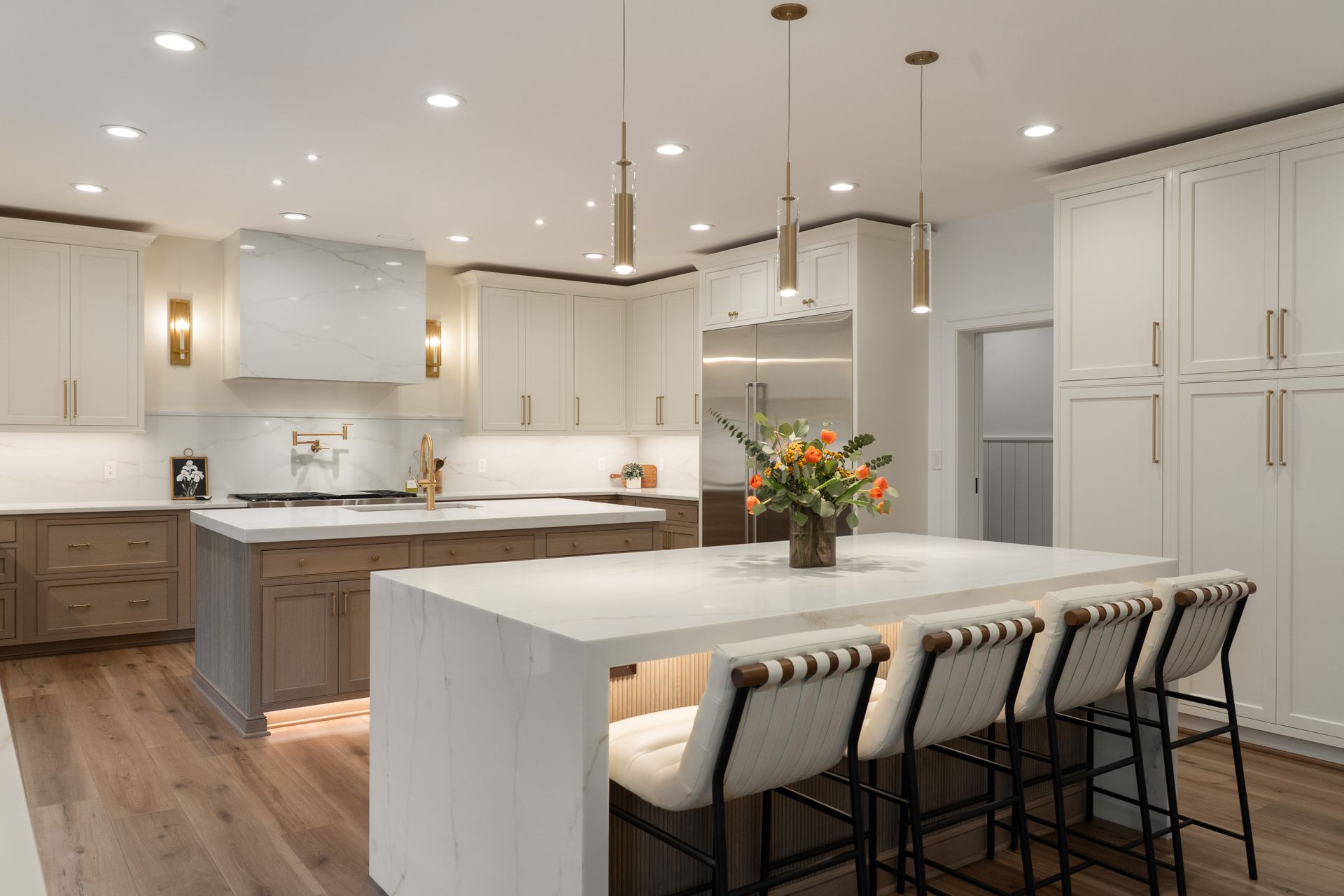 A kitchen with white cabinets , a large island , and stools.