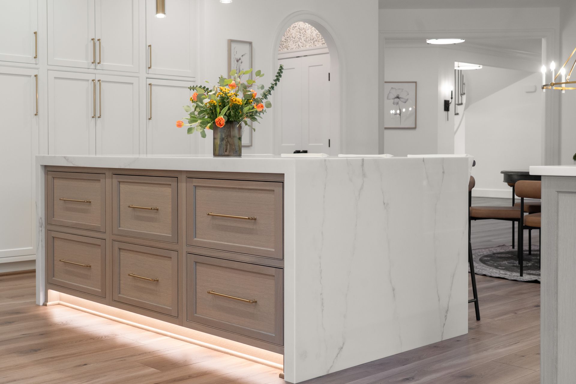 A kitchen with a large island and a vase of flowers on it.