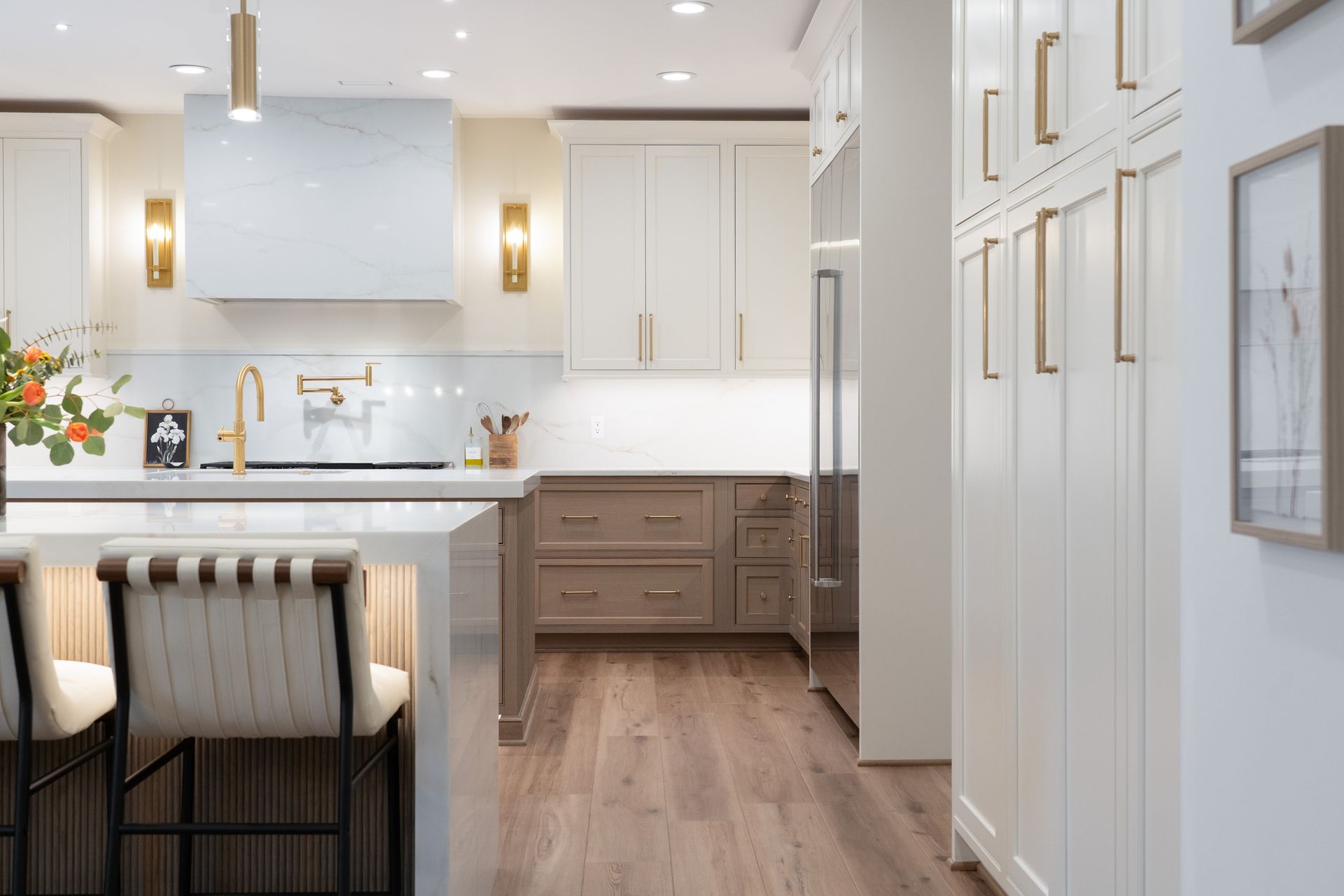 A kitchen with white cabinets and wooden floors and a large island.