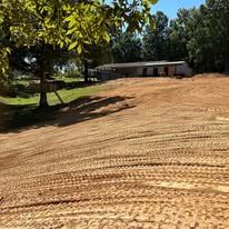 A large dirt field with a house in the background.