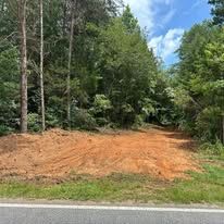 A dirt road going through a forest next to a road.