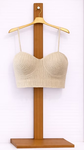 Top beige de ganchillo sin tirantes en una percha de madera.
