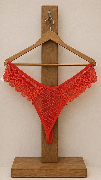 Tanga de encaje rojo en un soporte de madera contra una pared beige.