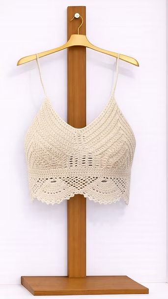 Un bralette de crochet color crema sobre un soporte de madera, sobre un fondo blanco.