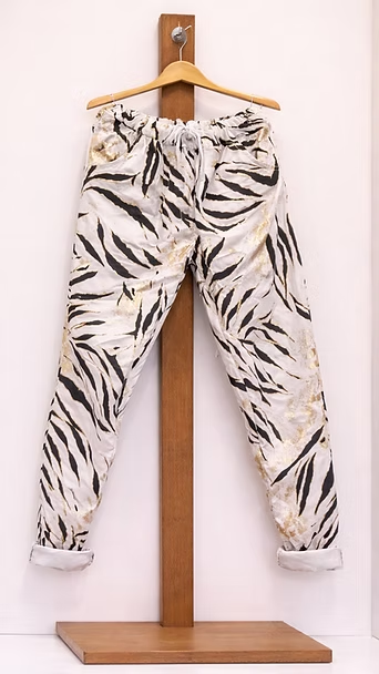 Pantalones estampados blancos y negros colgados en una percha de madera.