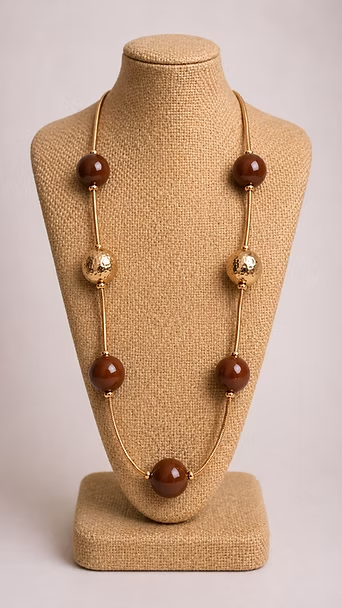 Collar de cuentas beige con cuentas marrones y doradas exhibido en el busto de un maniquí.