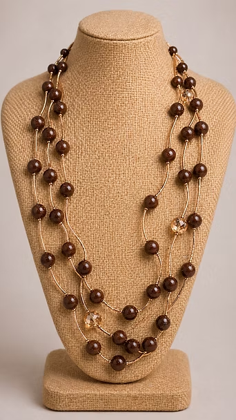 Collar de tres hileras de cuentas marrones sobre un soporte de exhibición con forma de busto beige.