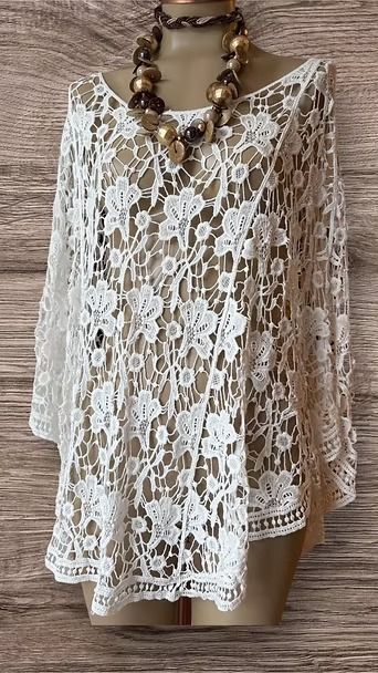 Blusa blanca de encaje floral con mangas largas y escote adornado con cuentas en un maniquí.
