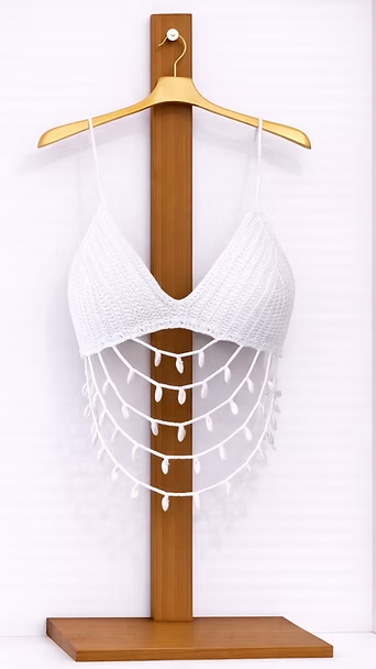 Top blanco de ganchillo con escote halter sobre un soporte de madera con flecos colgantes de cuentas.