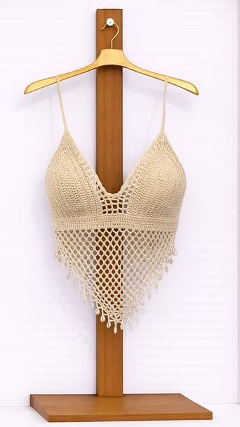 Top corto de ganchillo color beige en un soporte de madera.