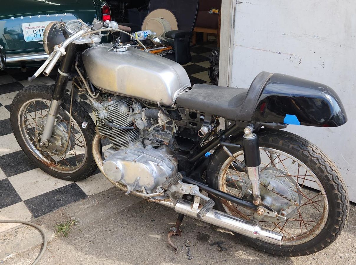 A motorcycle is parked in a garage next to a car.