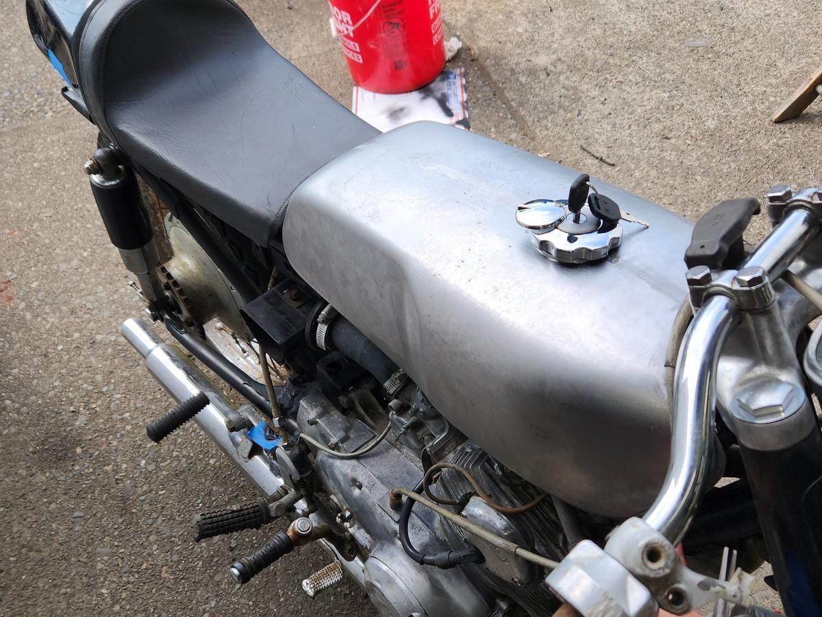 A silver motorcycle with a red bucket in the background