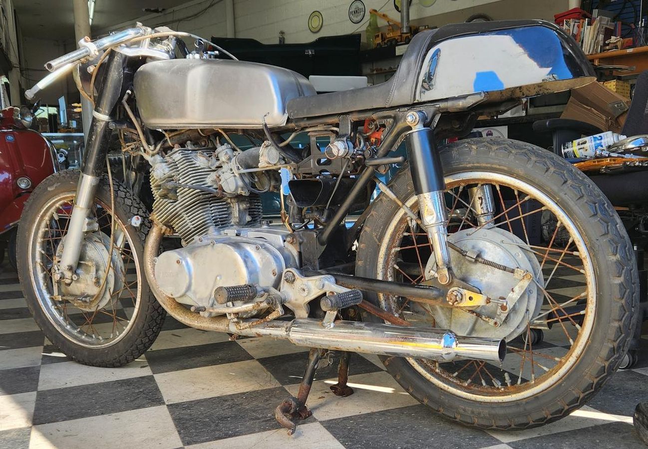 A motorcycle is parked on a checkered floor in a garage.