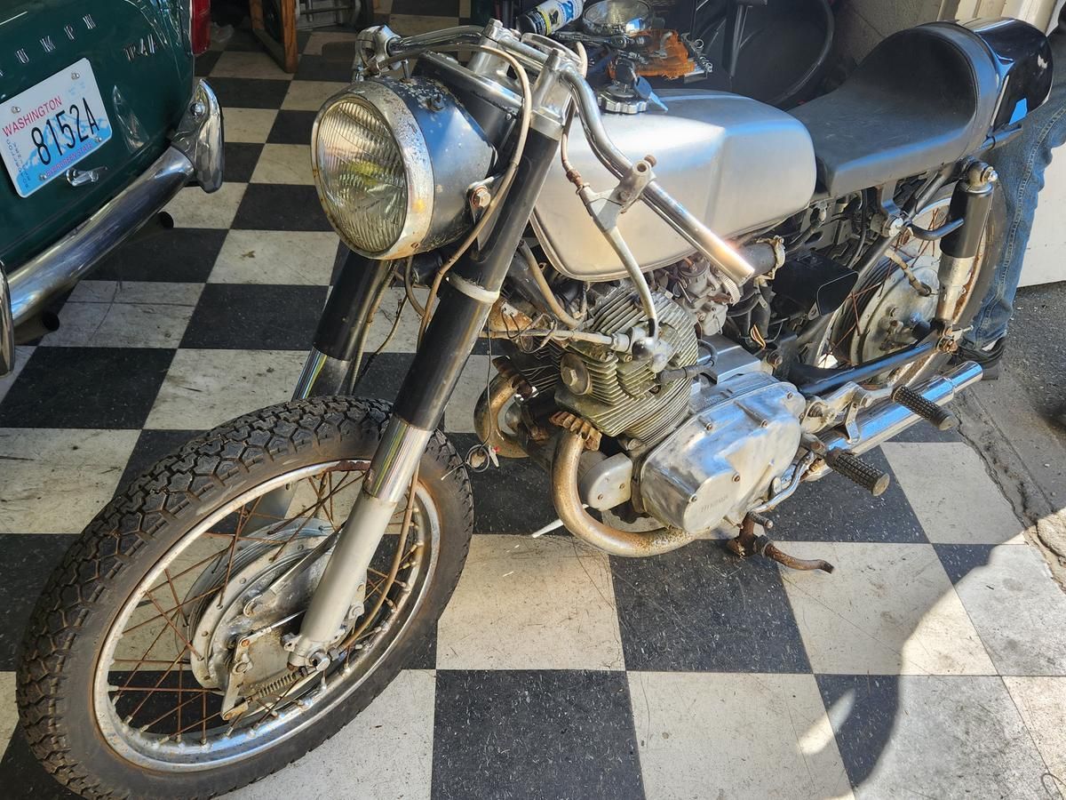 A motorcycle is parked on a checkered floor in a garage.