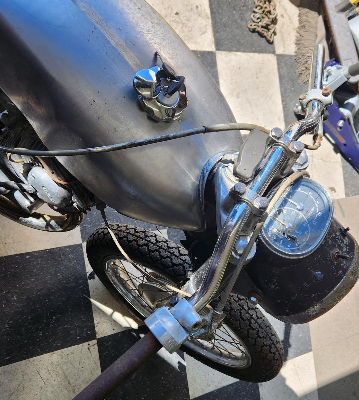 A silver motorcycle is parked on a checkered floor