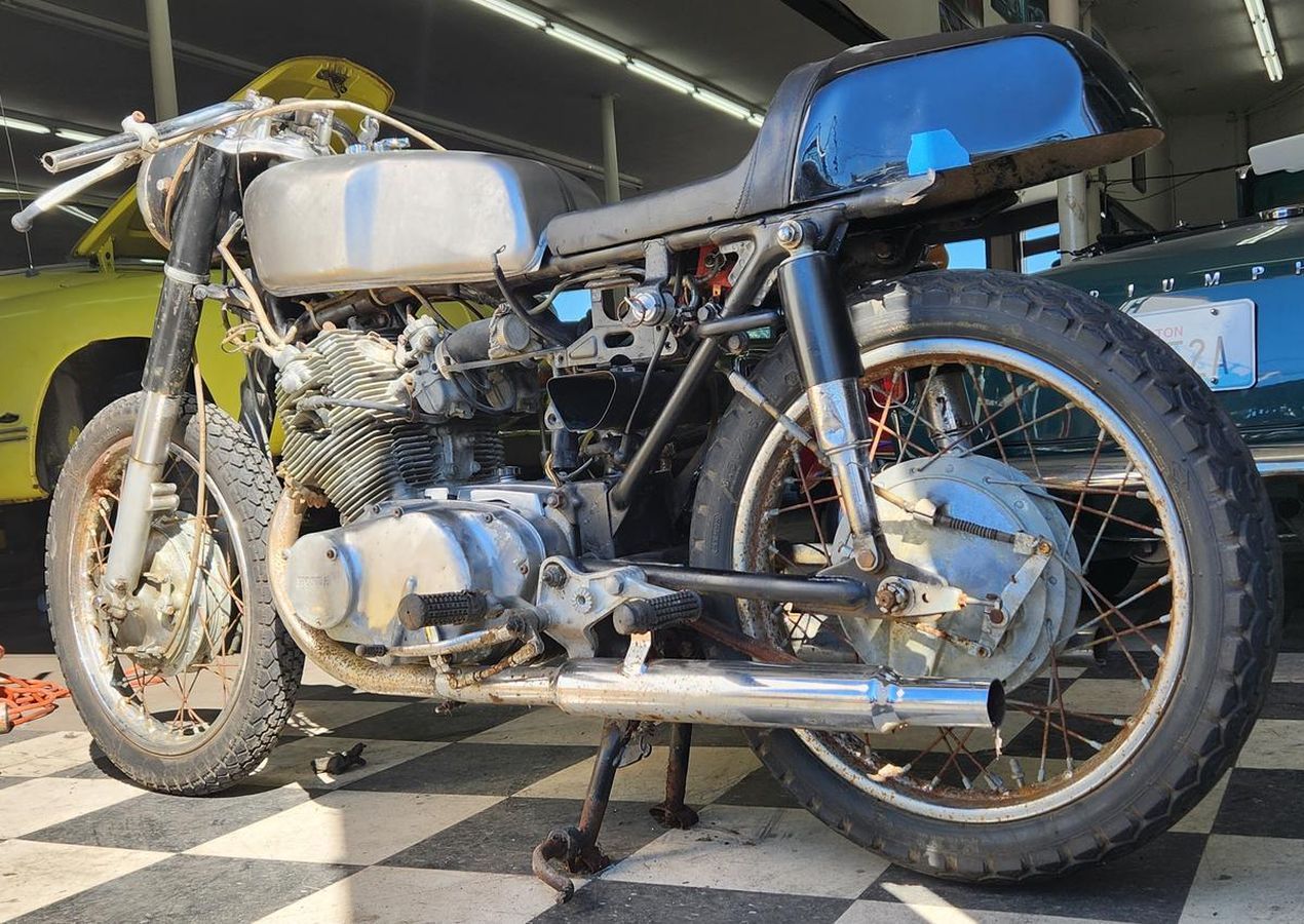A motorcycle is parked in a garage next to a yellow car.