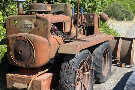 an old rusty tractor is parked on the side of the road