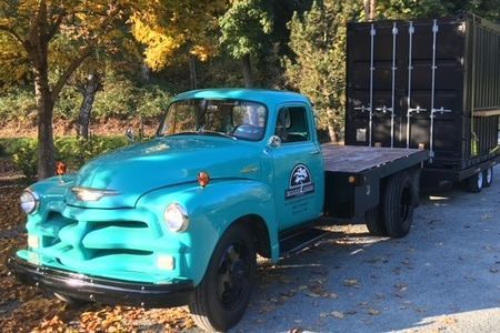 a blue truck is parked next to a black container