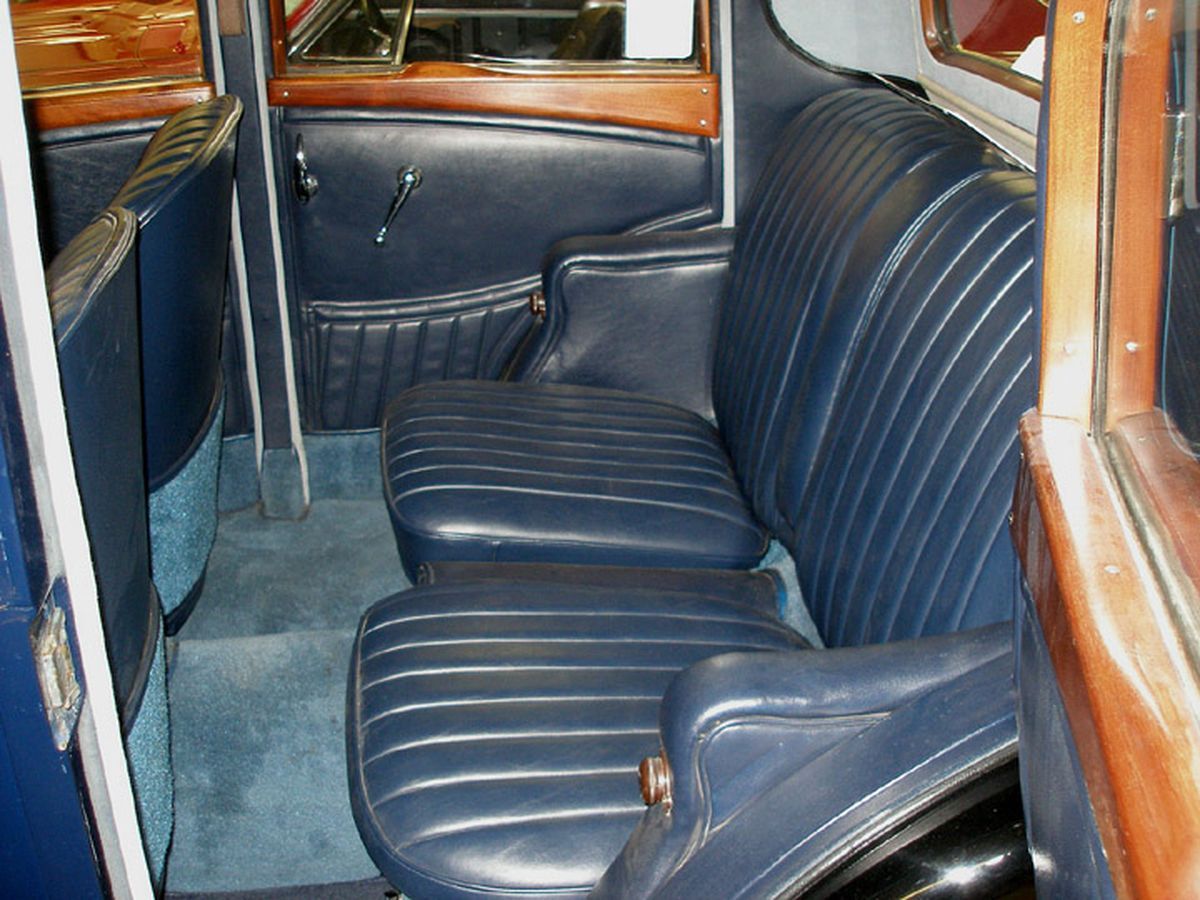 The back seat of an old car with blue leather seats
