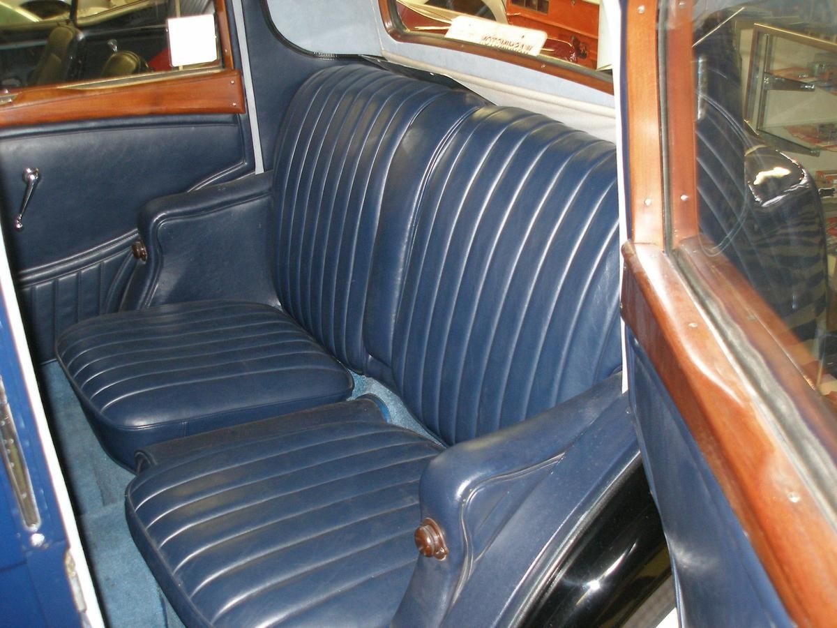 The back seat of an old car with blue leather seats