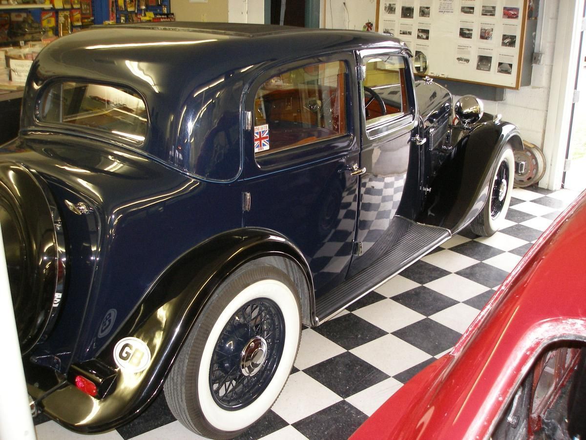 A black car with white tires is parked on a checkered floor