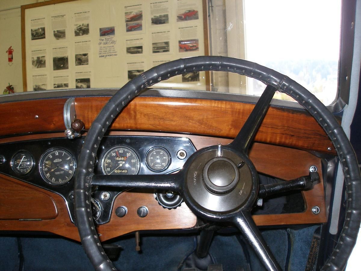 A steering wheel in an old car with a wooden dashboard