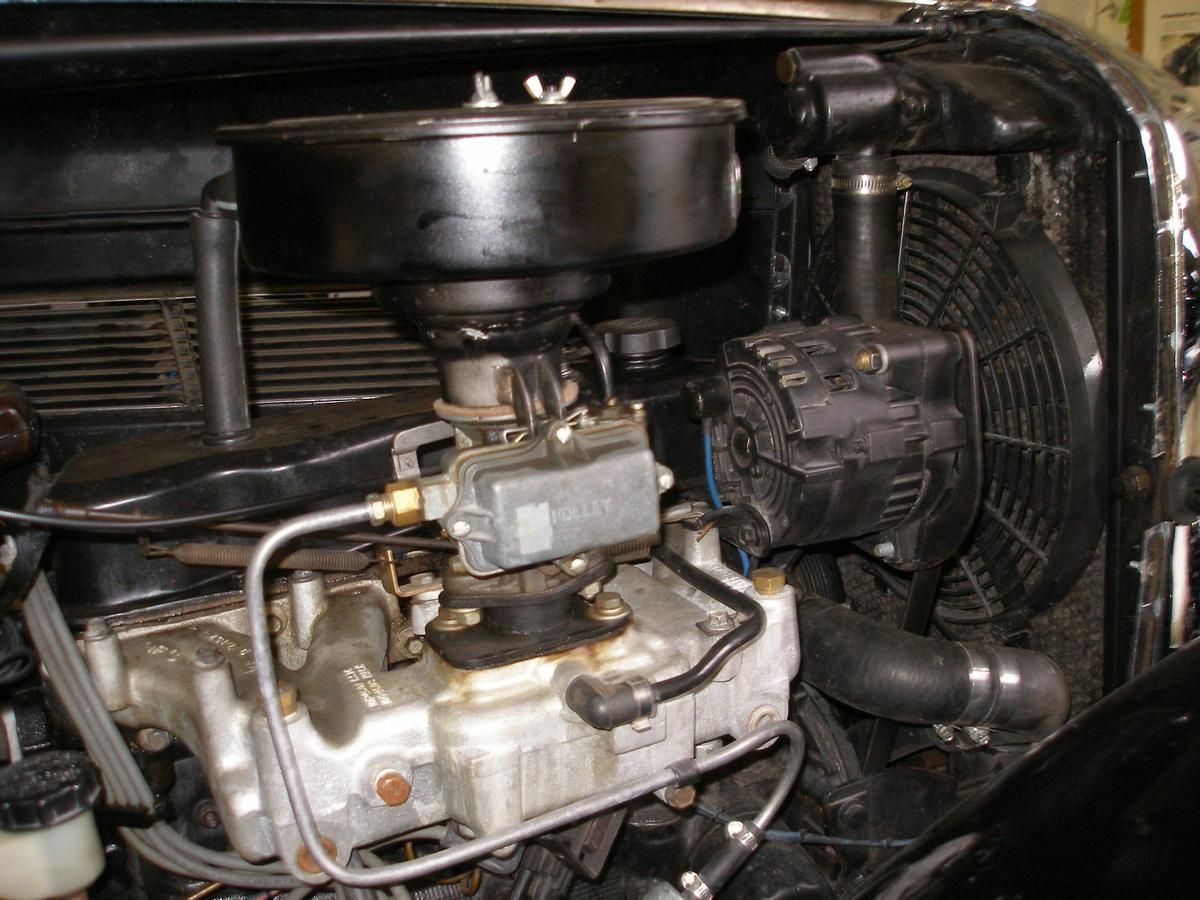 A close up of a car engine with a fan and air filter.